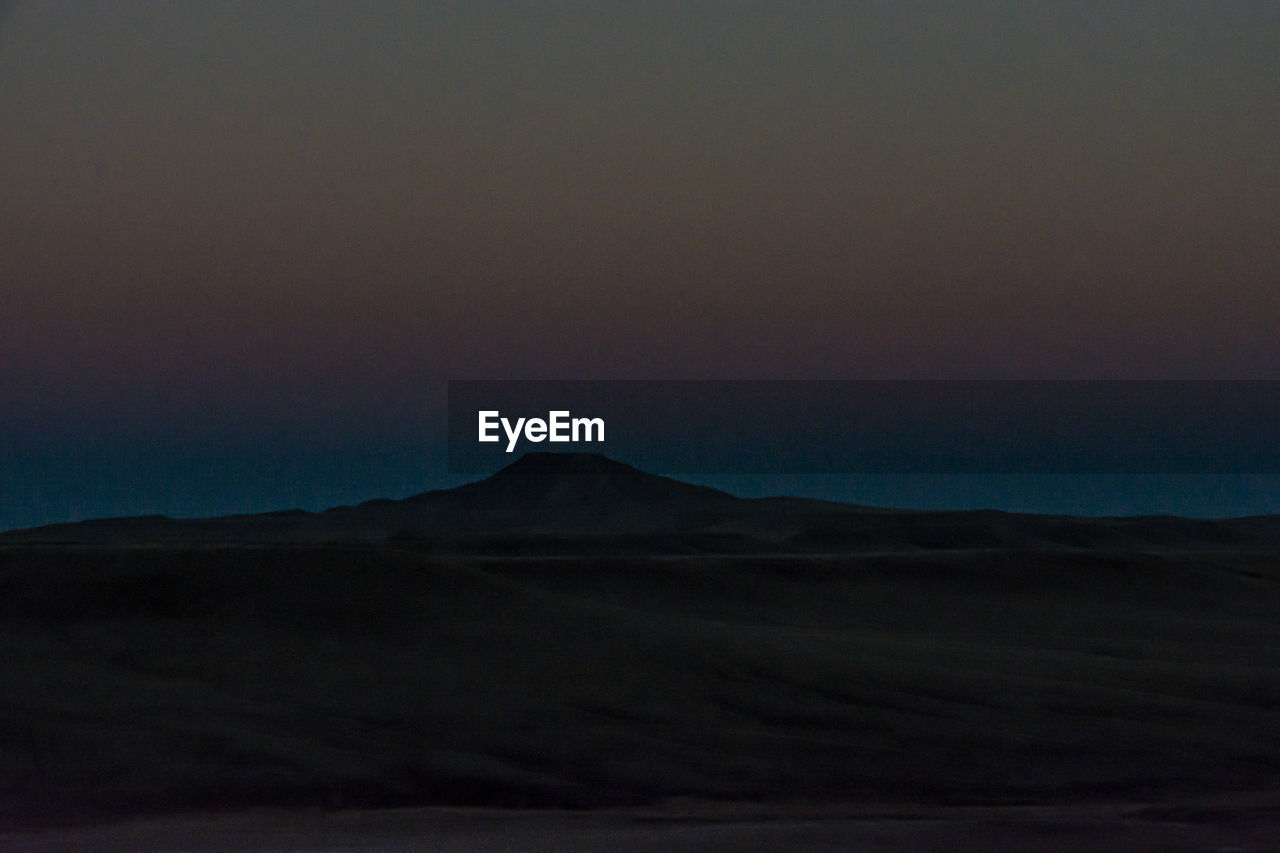 Scenic view of desert against sky at sunset