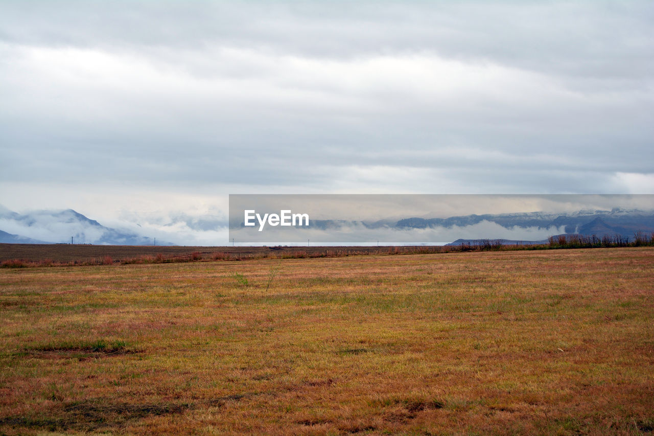 Scenic view of grassy field against cloudy sky