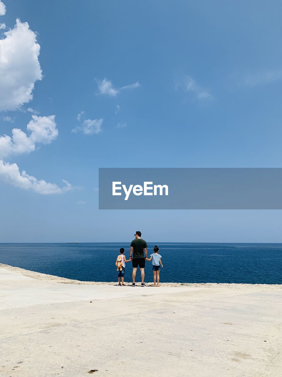 MEN ON BEACH AGAINST SEA AGAINST SKY