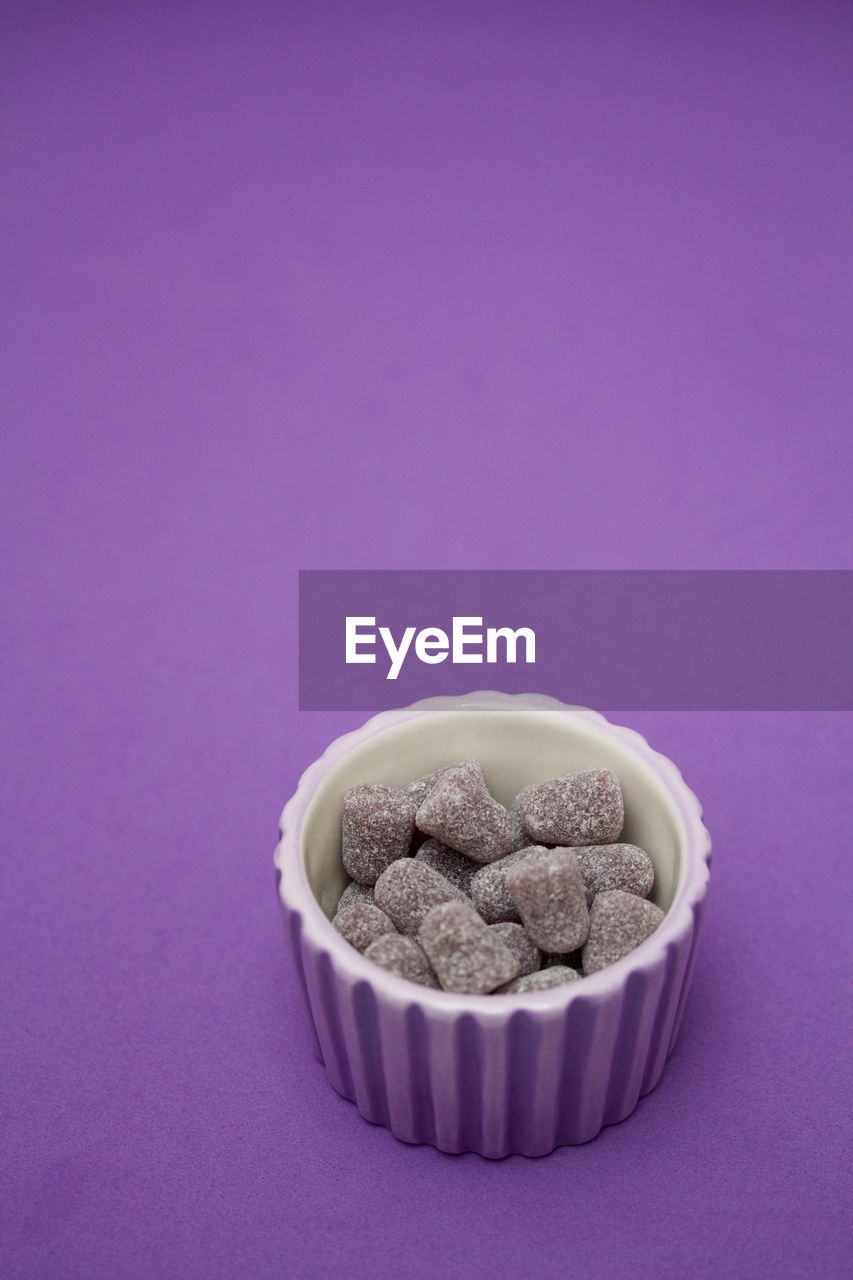 Purple rubber bullets in a purple little bowl on purple background