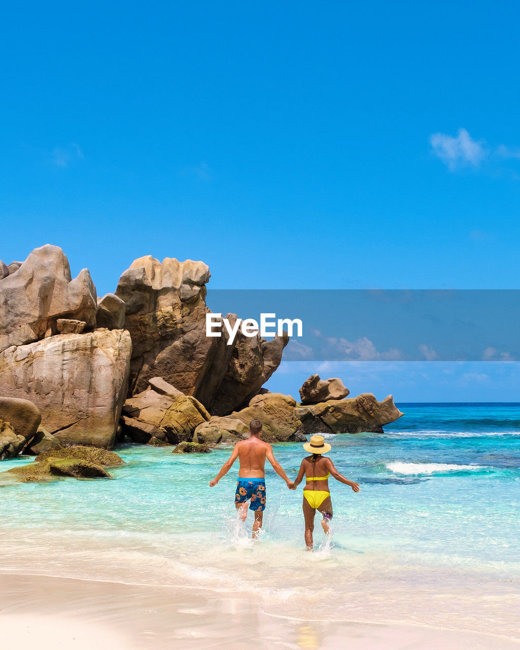 rear view of woman walking at beach against blue sky