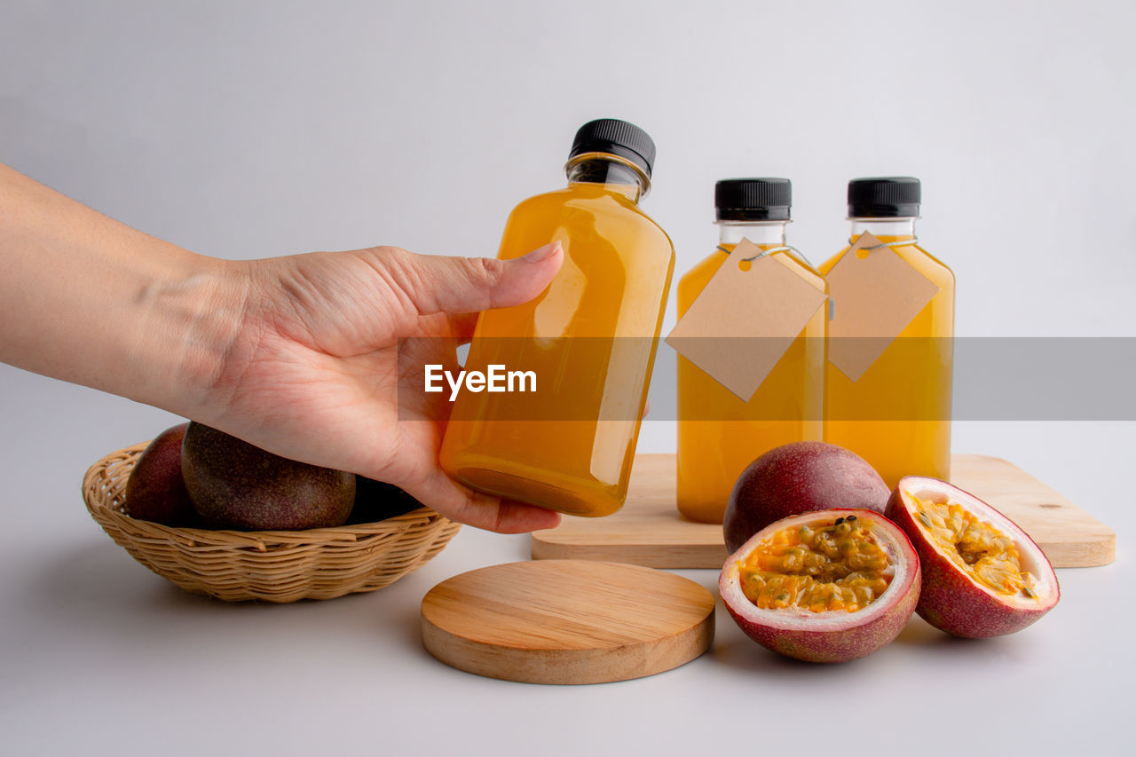 Fresh passion fruit juice in in plastic bottles with passion fruits on white background.