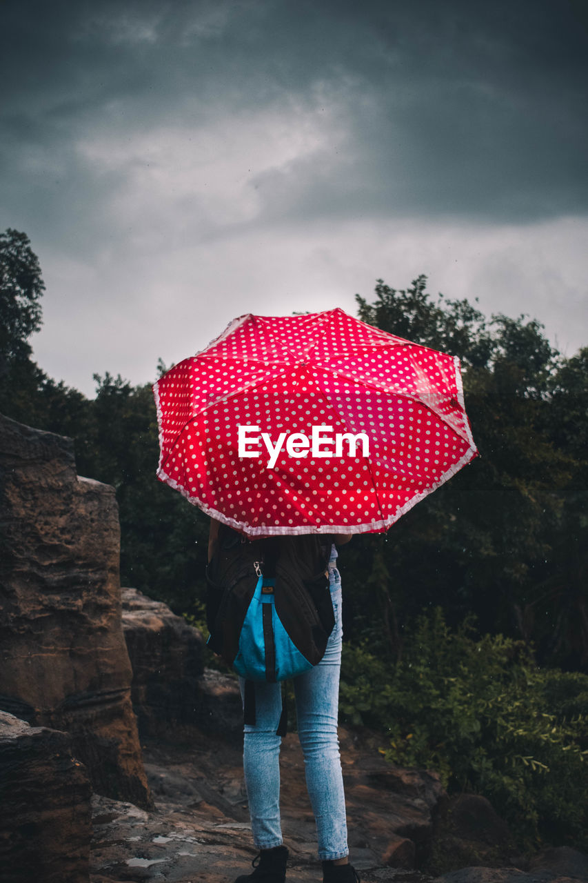 Rear view of woman with umbrella standing in rain