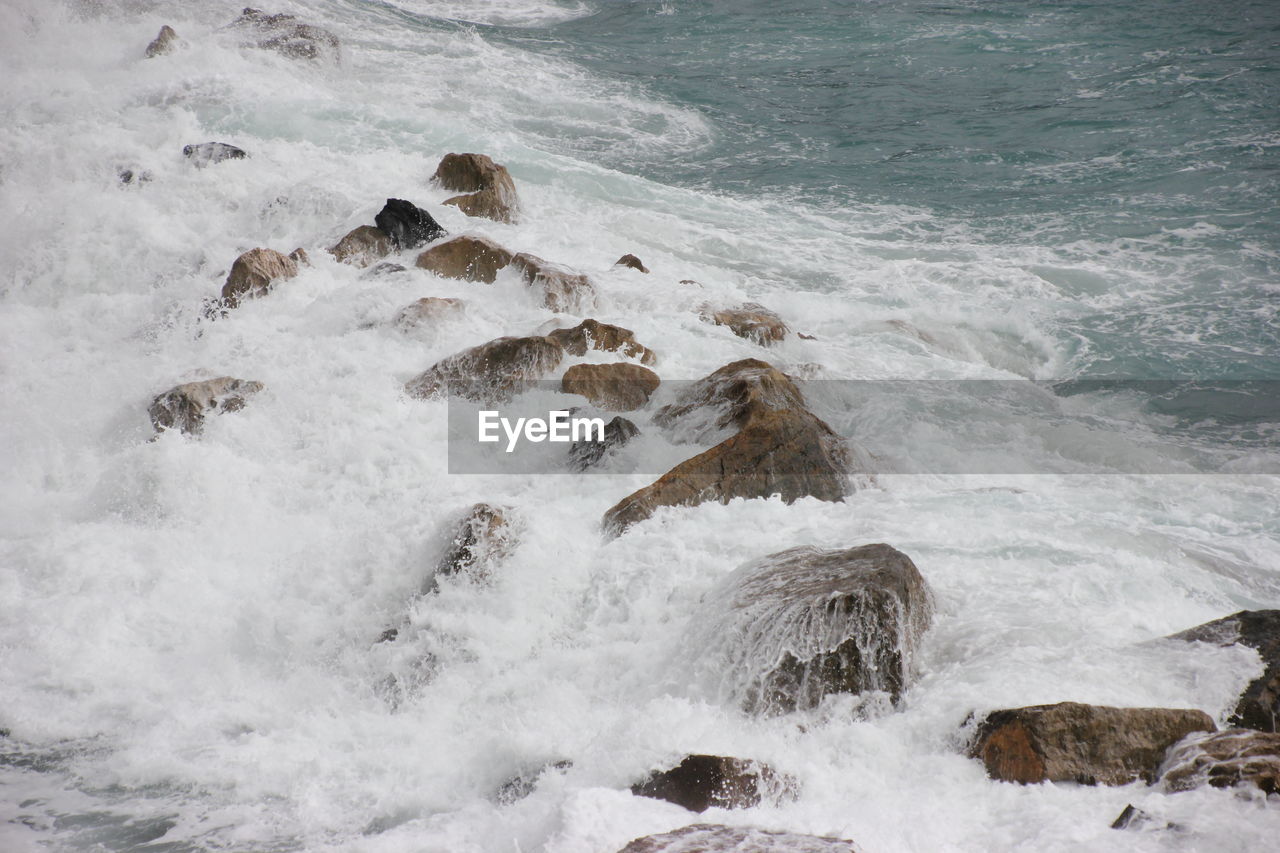 High angle view of waves splashing on rocks