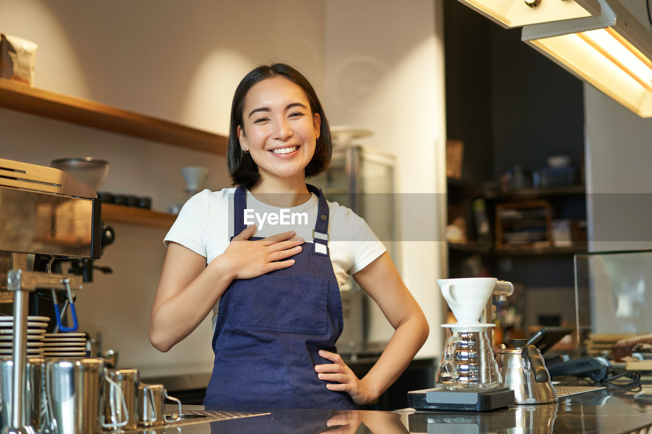 portrait of smiling young woman standing in cafe