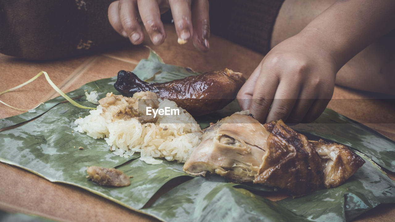 Close-up of hand eating food in banana leaf 