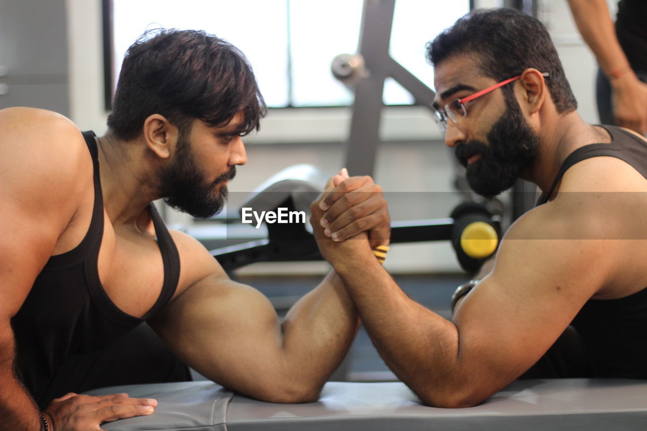 Male friends arm wrestling at gym
