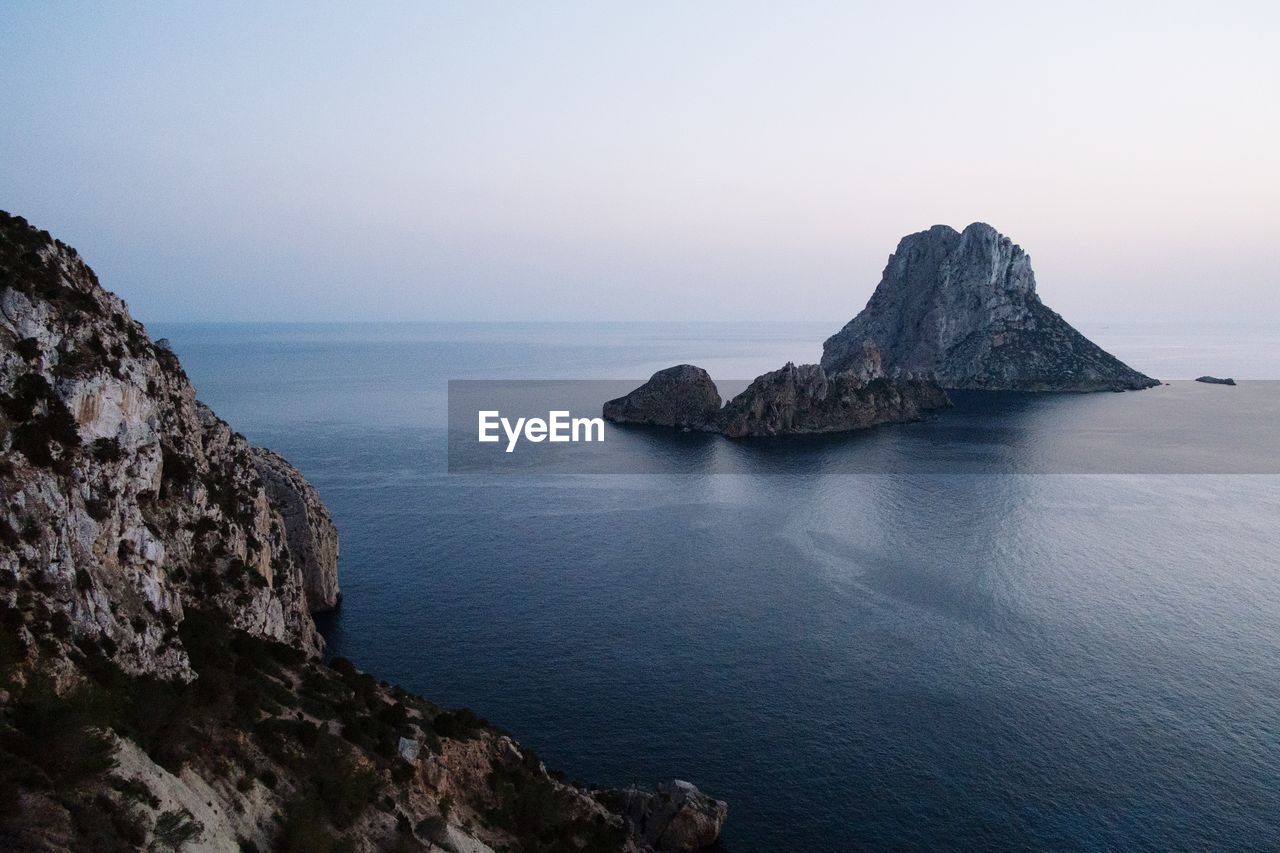 Rock formation in sea against clear sky