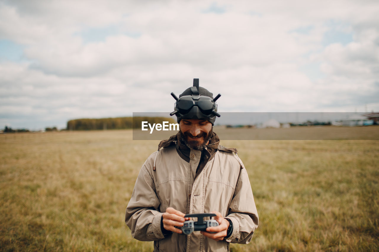Portrait of man standing on field against sky