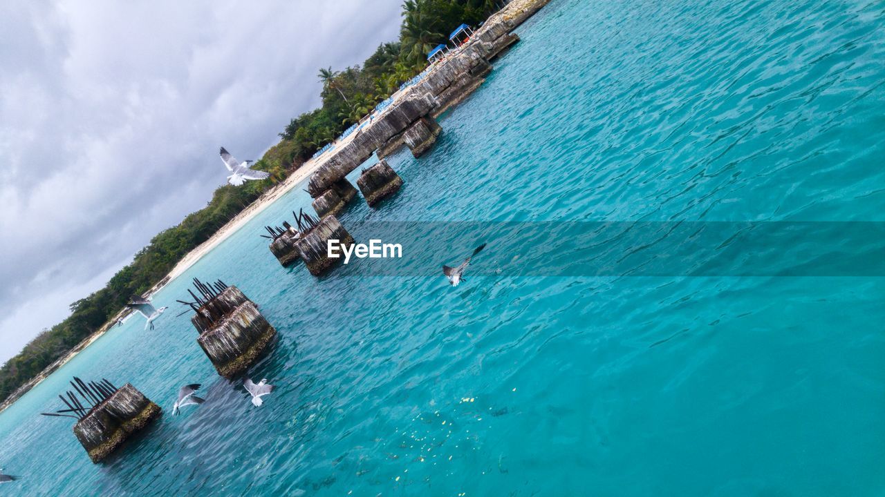 LOW ANGLE VIEW OF SWIMMING IN SEA AGAINST SKY