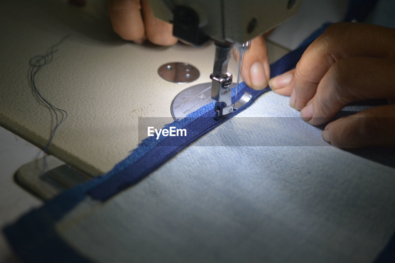 Close-up of hands working on sewing machine