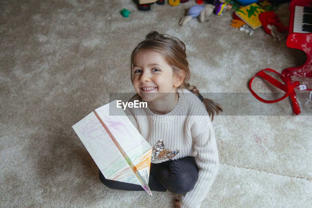 High angle portrait of girl playing with paper airplane 