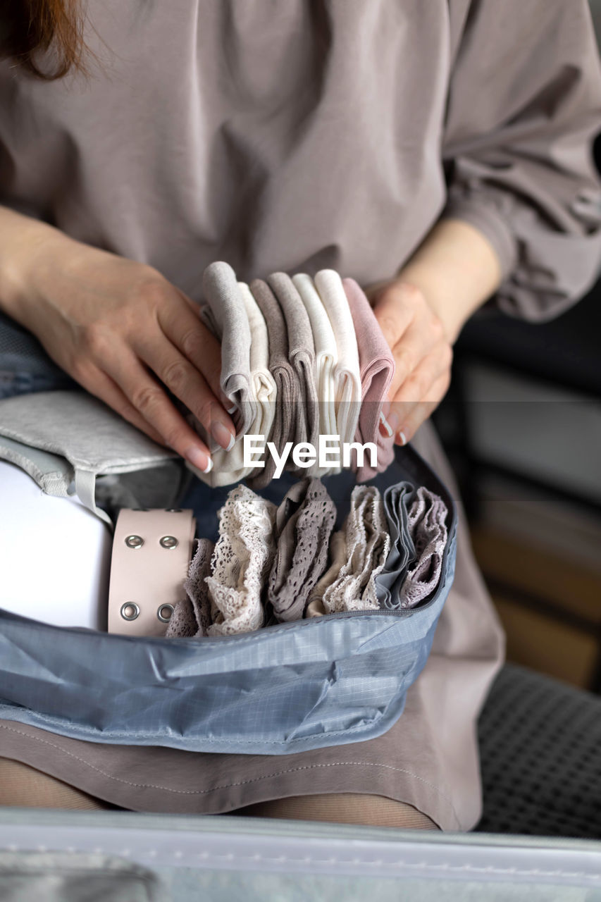 Midsection of woman holding clothes at home