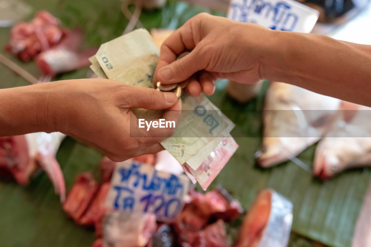 CLOSE-UP OF HAND HOLDING PAPER WITH TATTOO ON HANDS