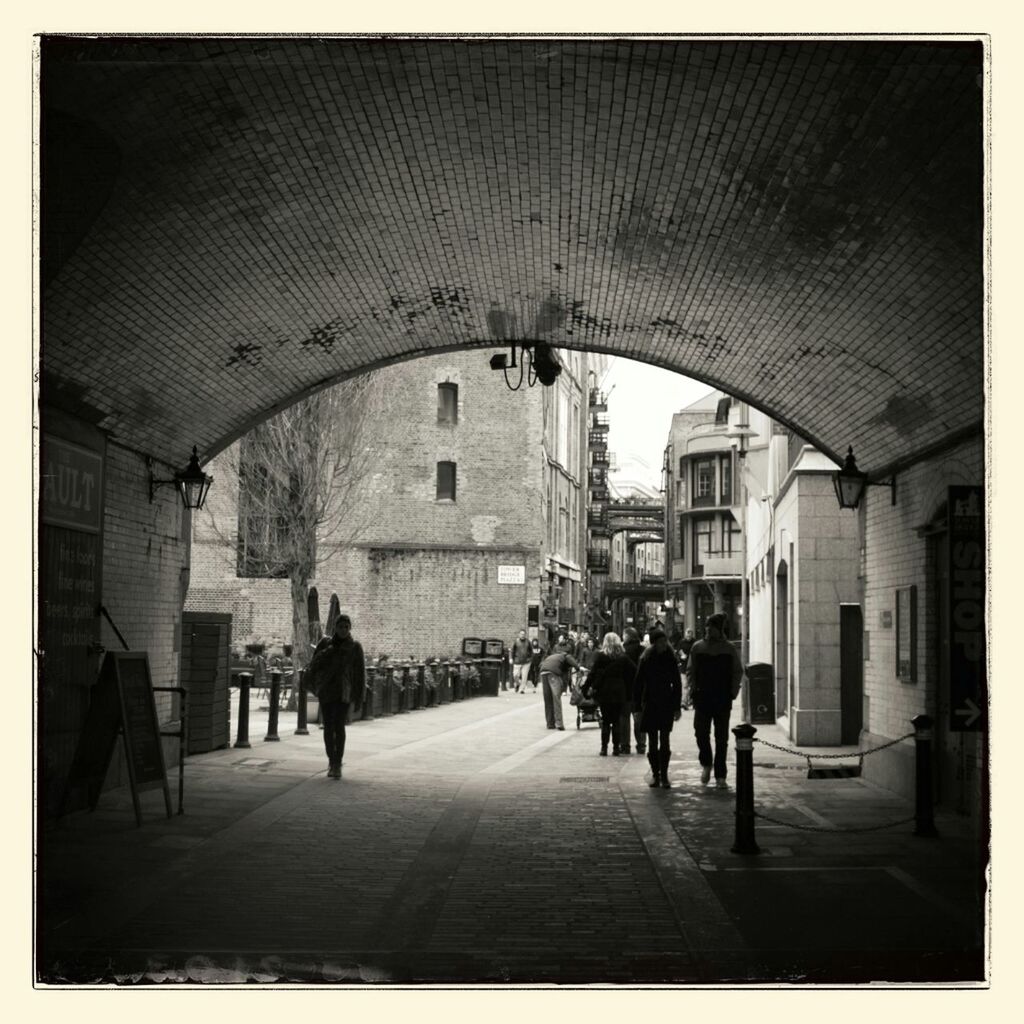 People walking under archway in city