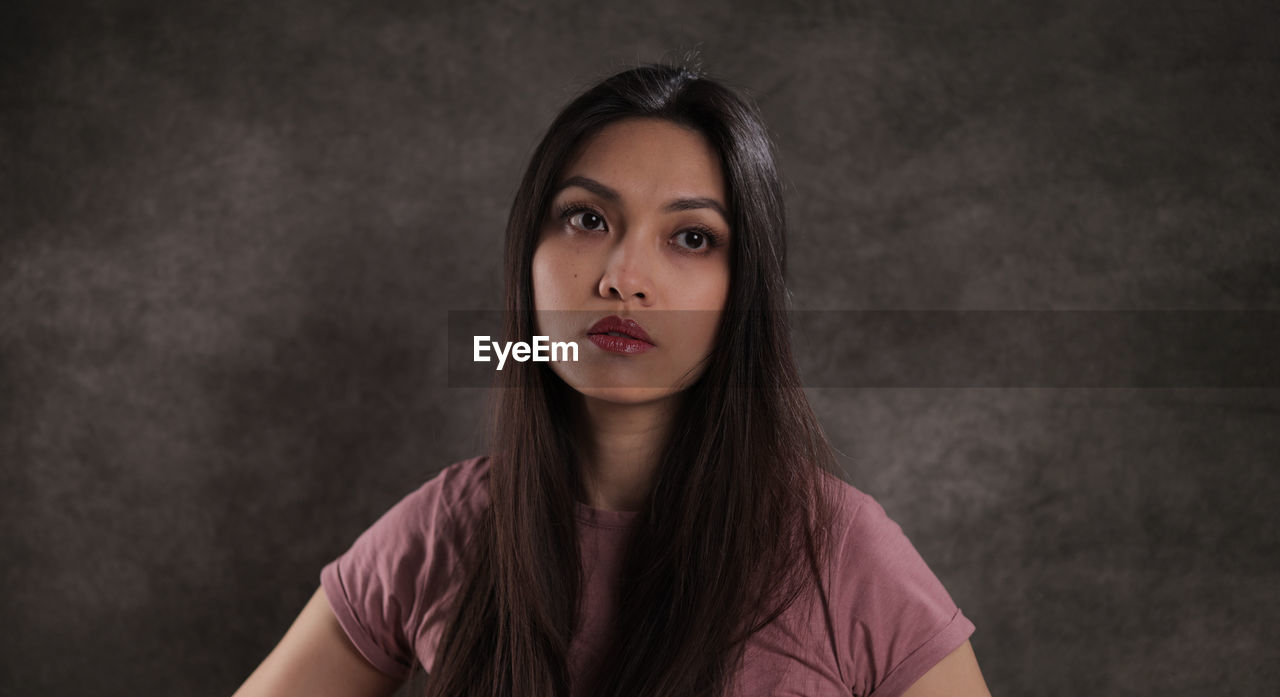 portrait of beautiful young woman against black background