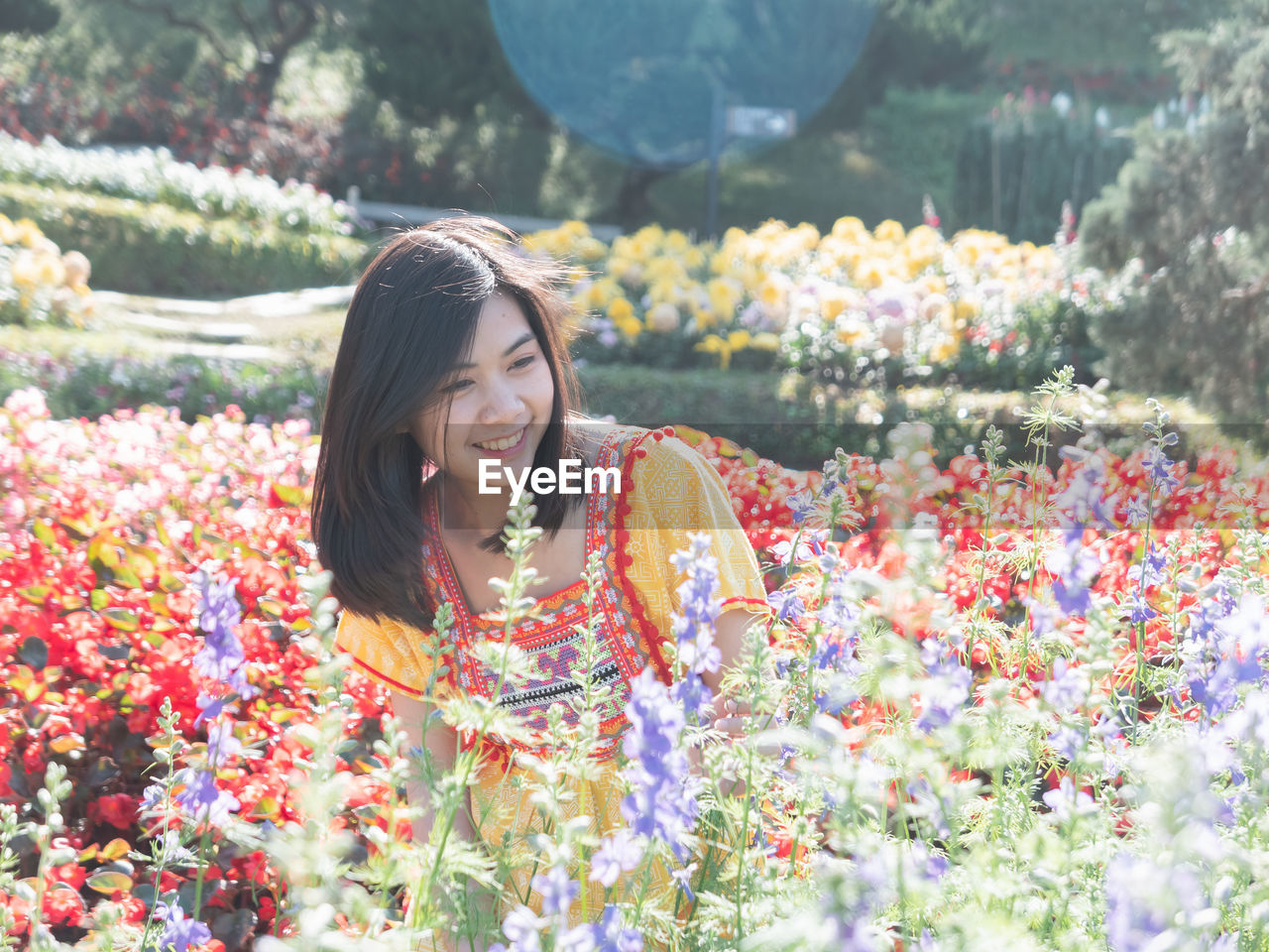 Smiling young woman looking at flowers in park