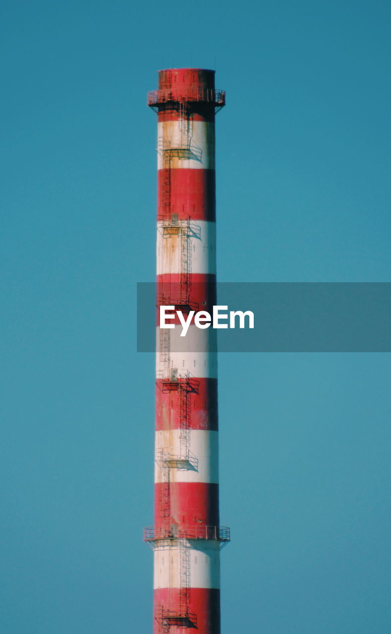 Low angle view of smoke stack against clear blue sky