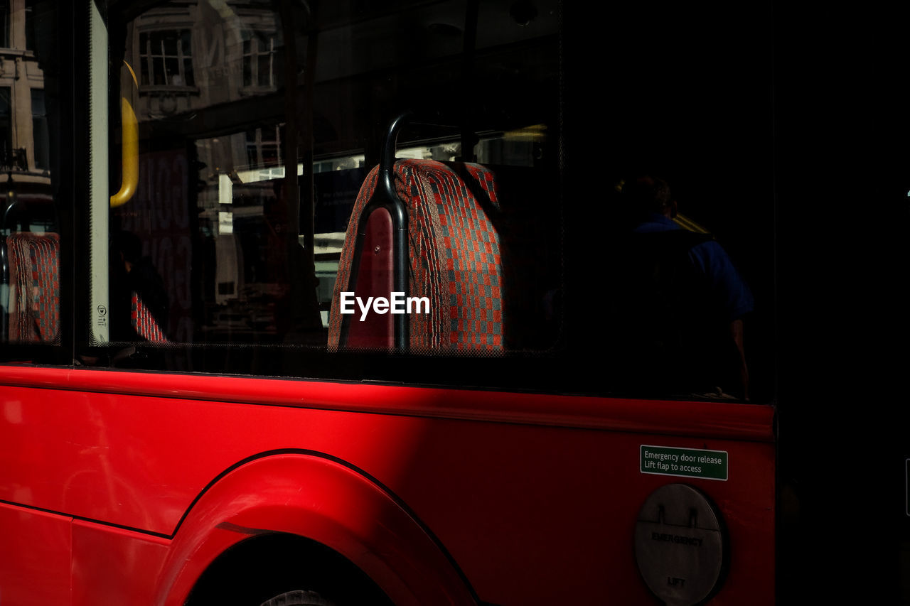 REAR VIEW OF MAN STANDING ON RED BUS