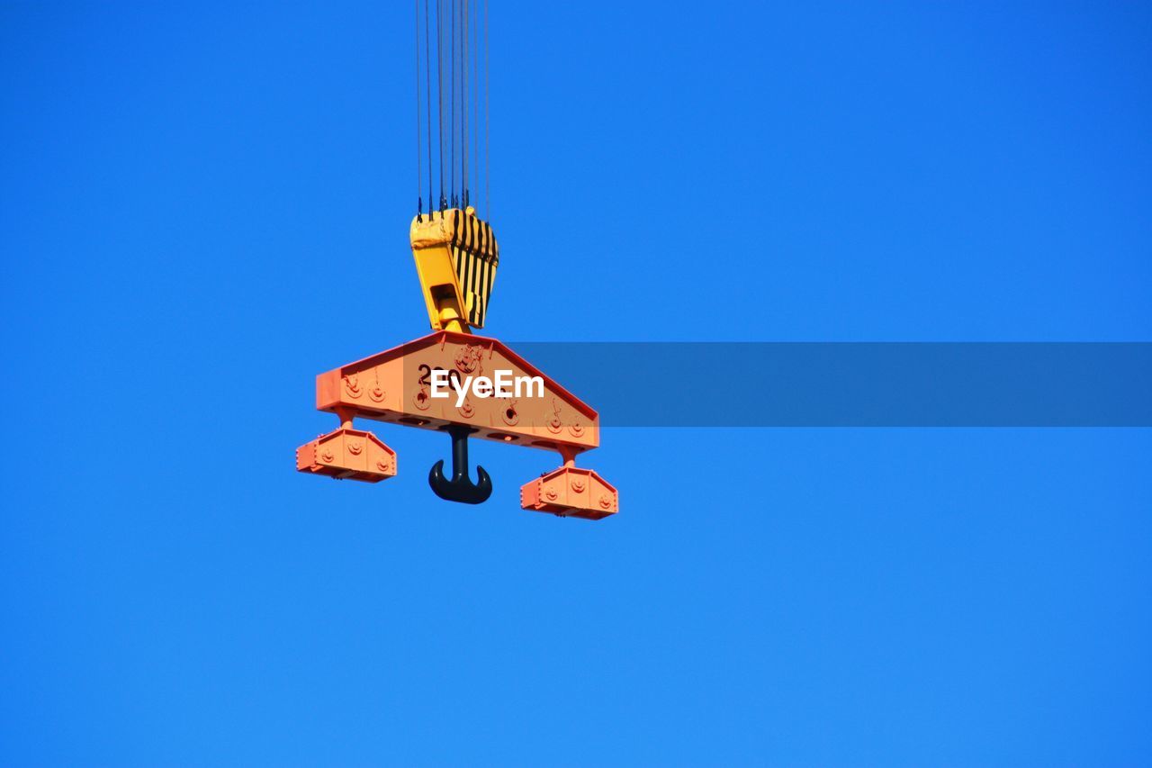Low angle view of crane pulley against clear blue sky