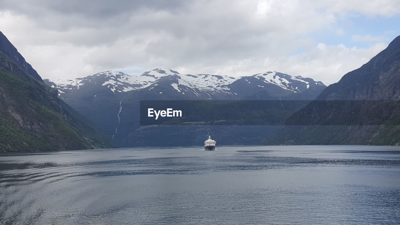 Scenic view of lake and mountains against cloudy sky