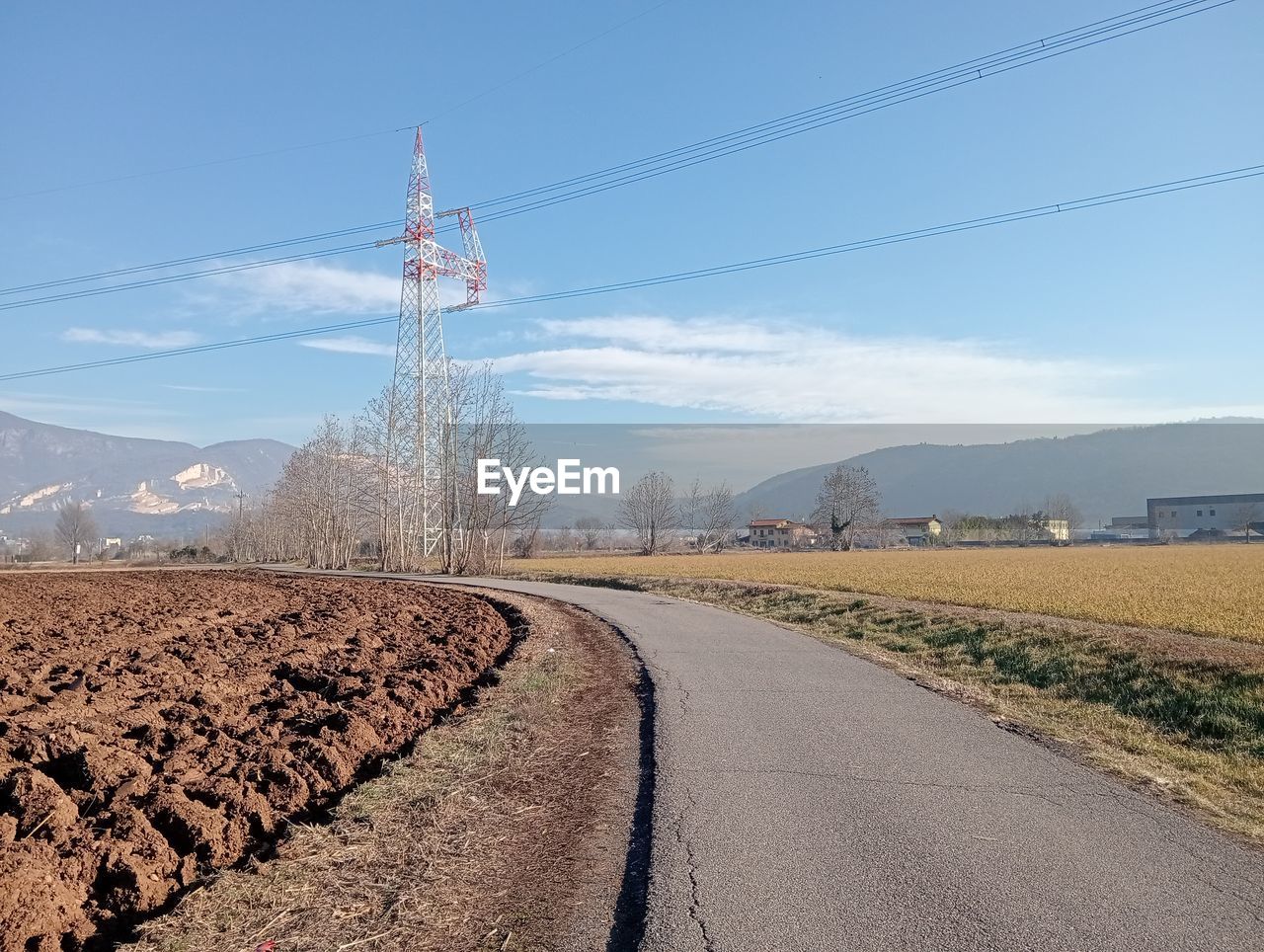 electricity, sky, cable, technology, electricity pylon, landscape, nature, transportation, road, power line, field, power supply, horizon, power generation, environment, land, no people, mountain, soil, scenics - nature, day, rural area, plant, rural scene, blue, track, outdoors, cloud, the way forward, transport, diminishing perspective, highway, agriculture, beauty in nature, vanishing point, non-urban scene, tree, sunlight, tranquility, clear sky, mountain range, overhead power line, infrastructure