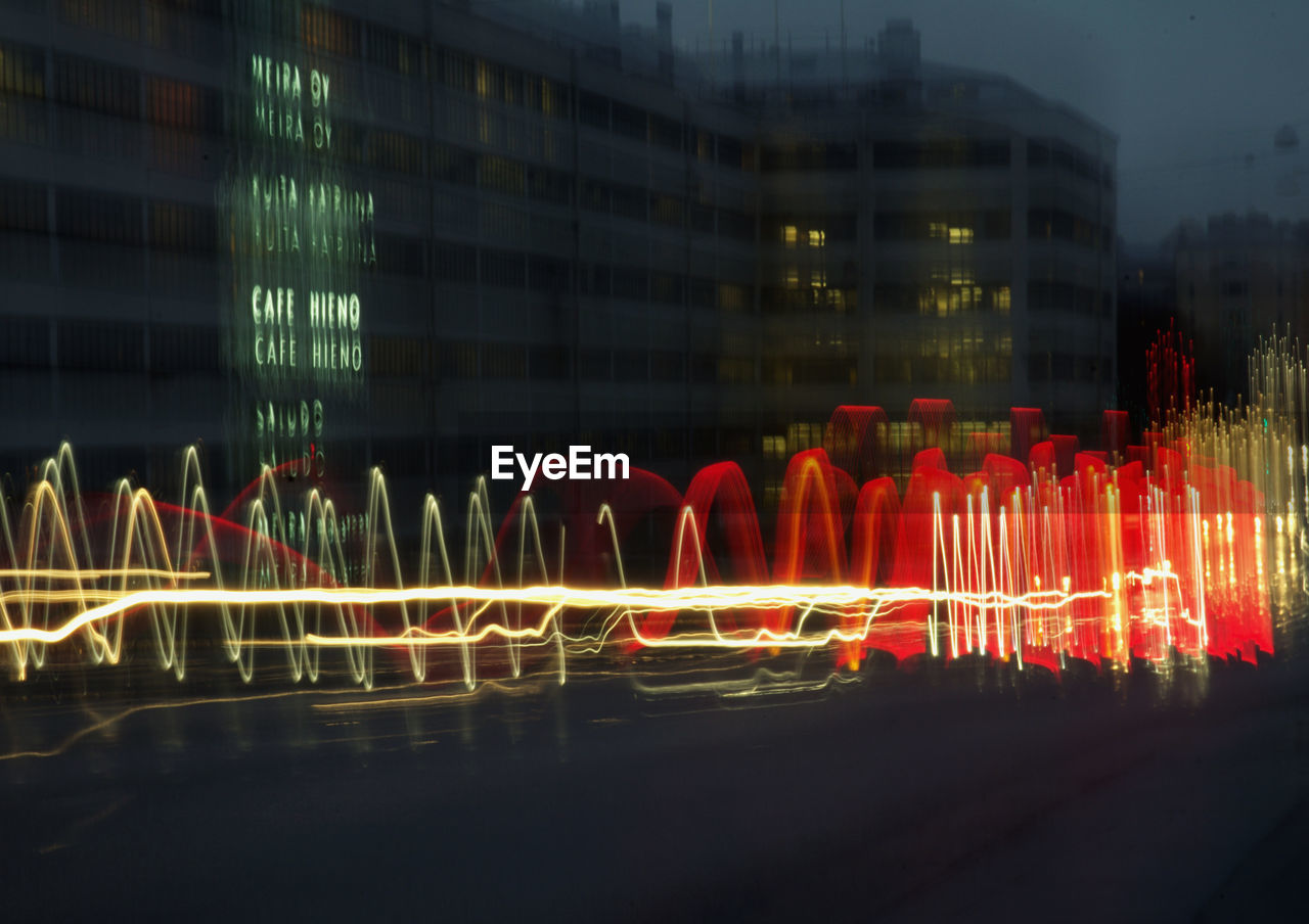 Light trails in city against buildings at night