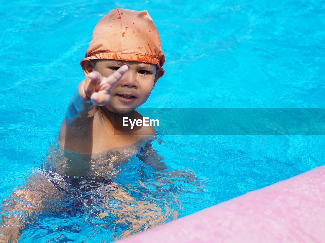 Portrait of boy gesturing while swimming in pool