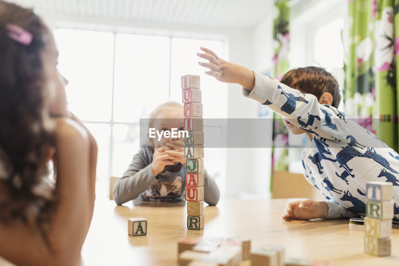 Boy stacking alphabet blocks on table