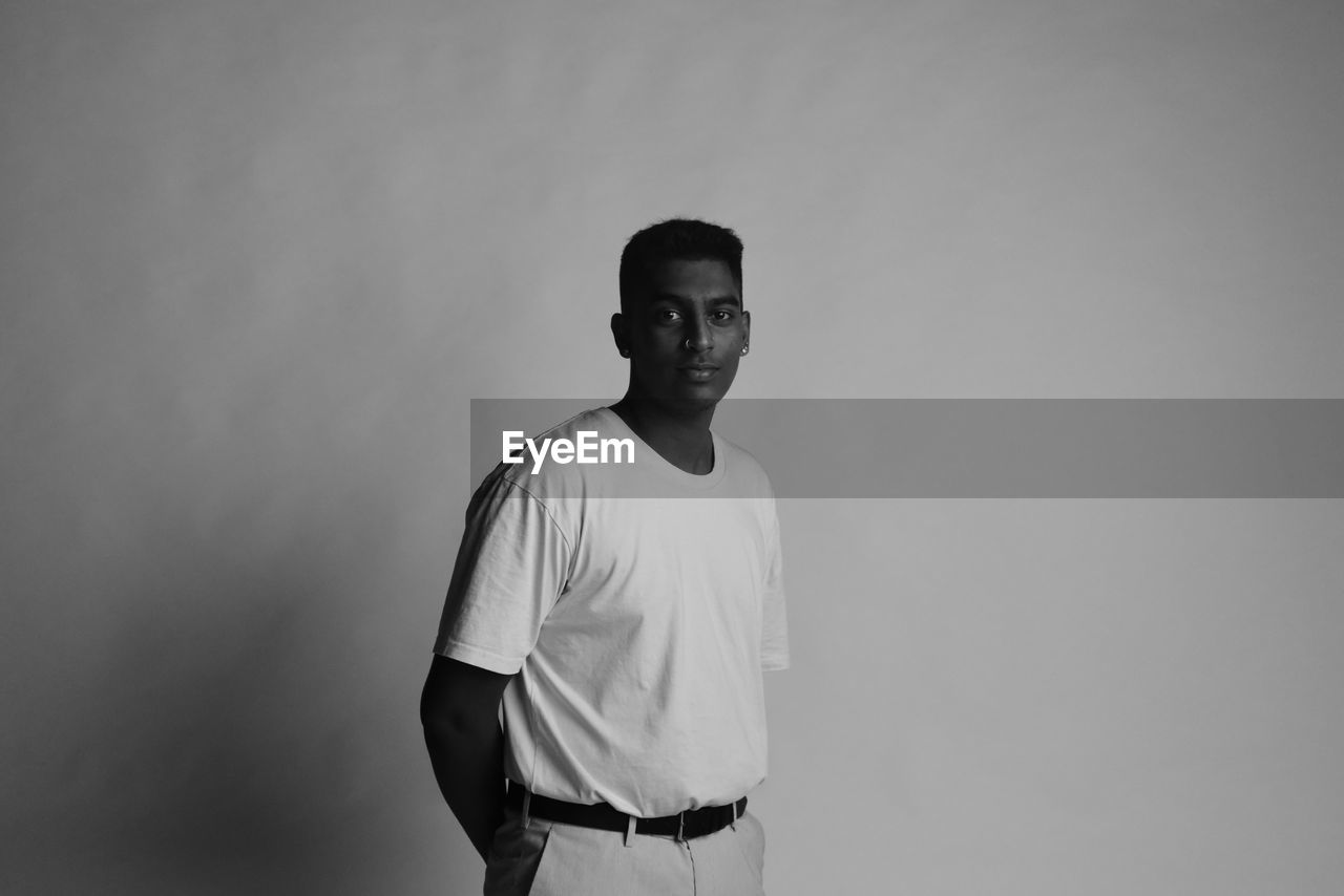 Portrait of young man standing against backdrop