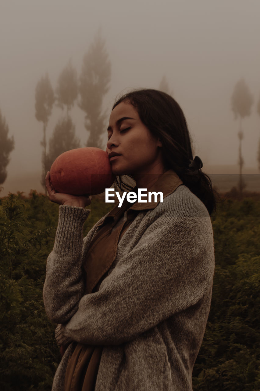 Side view of woman holding pumpkin