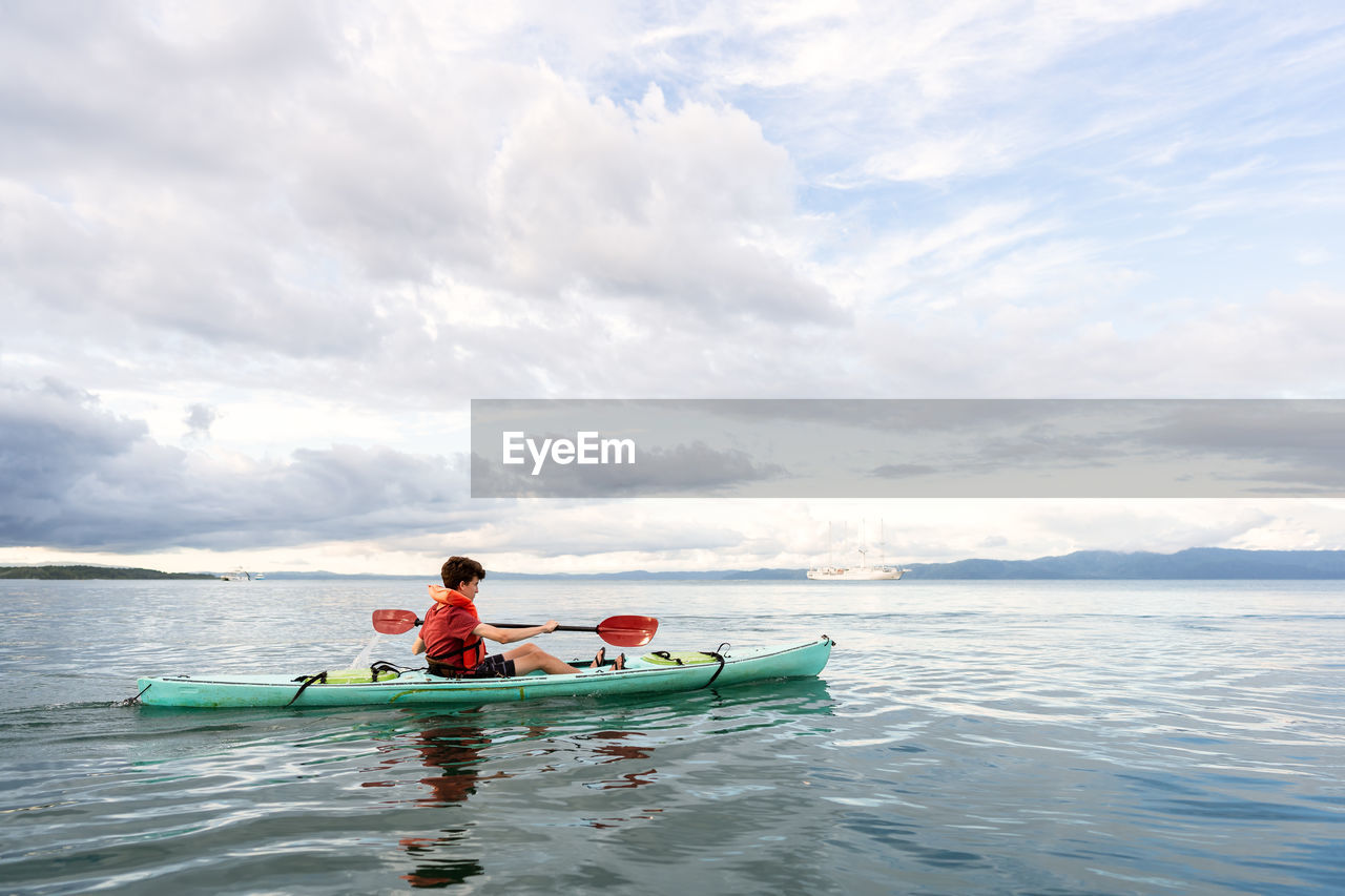 Teenager paddling kayak in costa rica