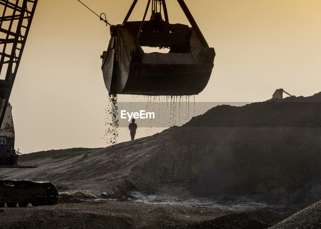 Man walking at construction site during sunset