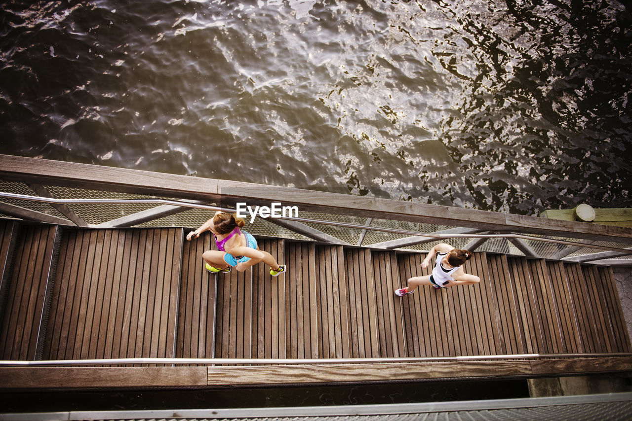 High angle view of friends jogging on steps by river