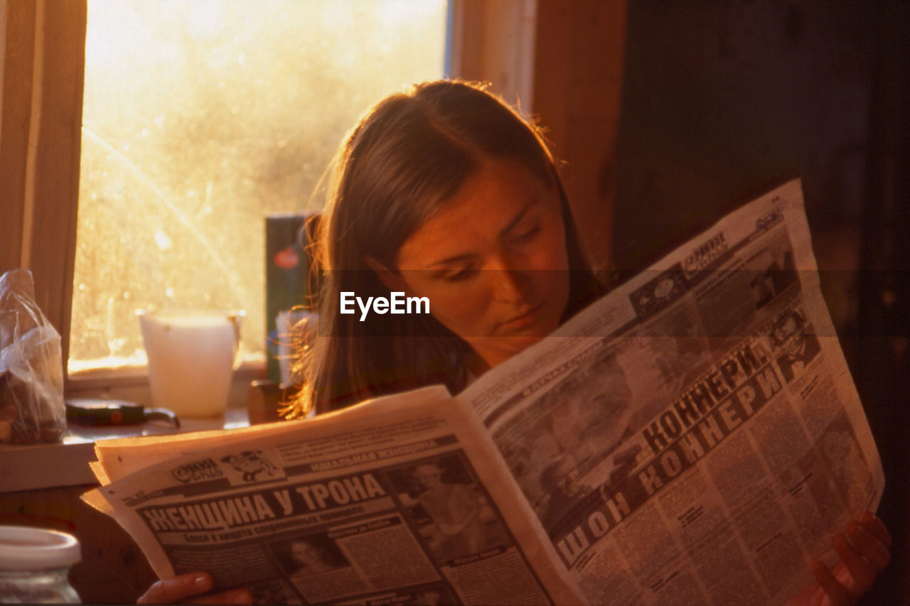 Woman reading newspaper at home