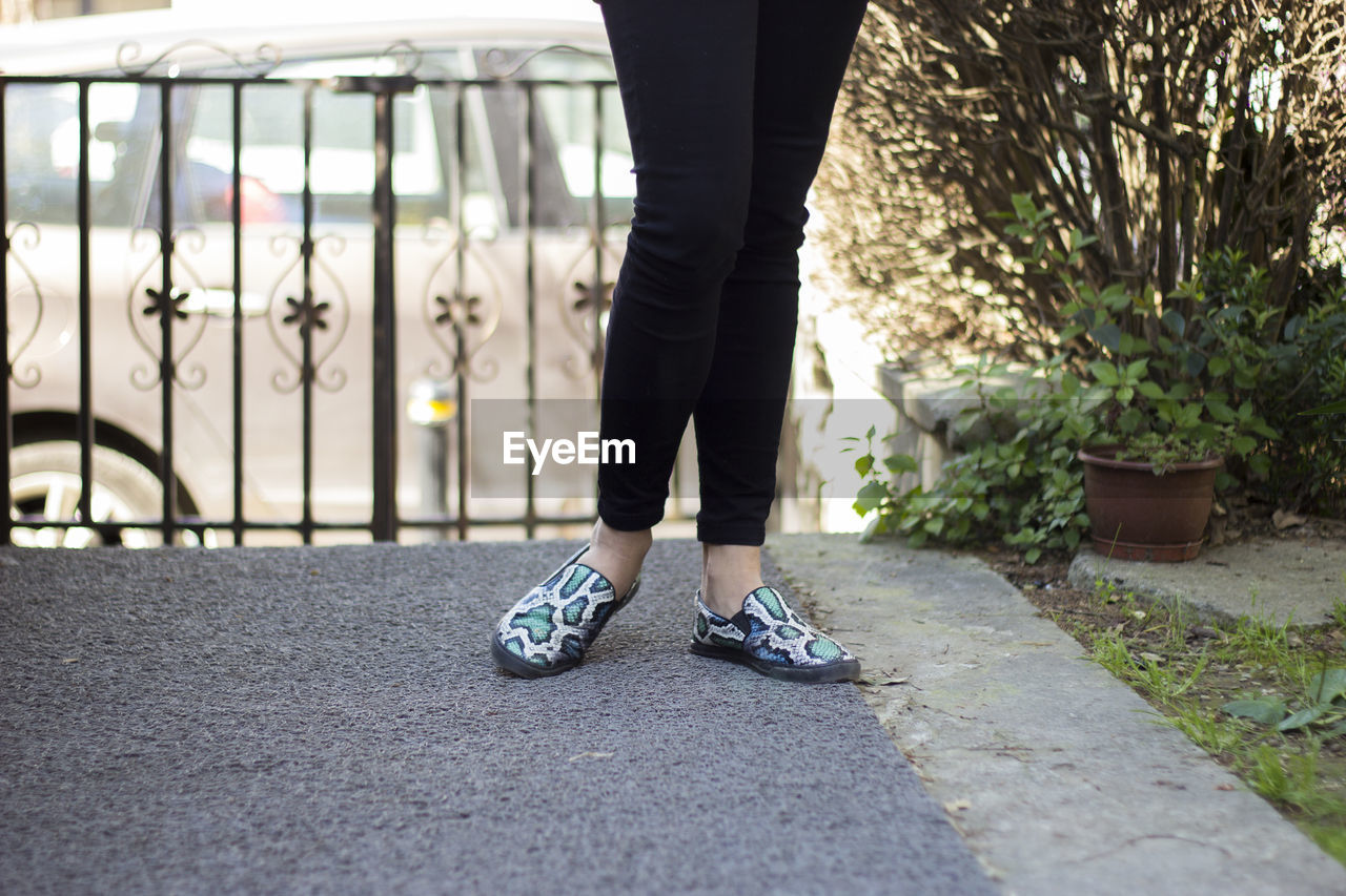 Low section of woman standing on footpath