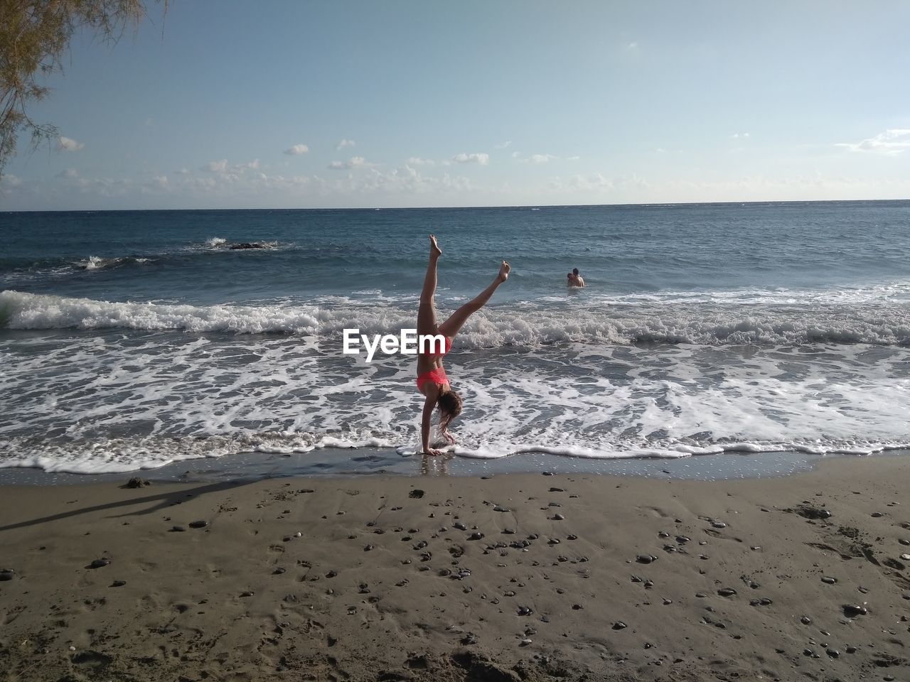 Woman doing handstand at beach against sky