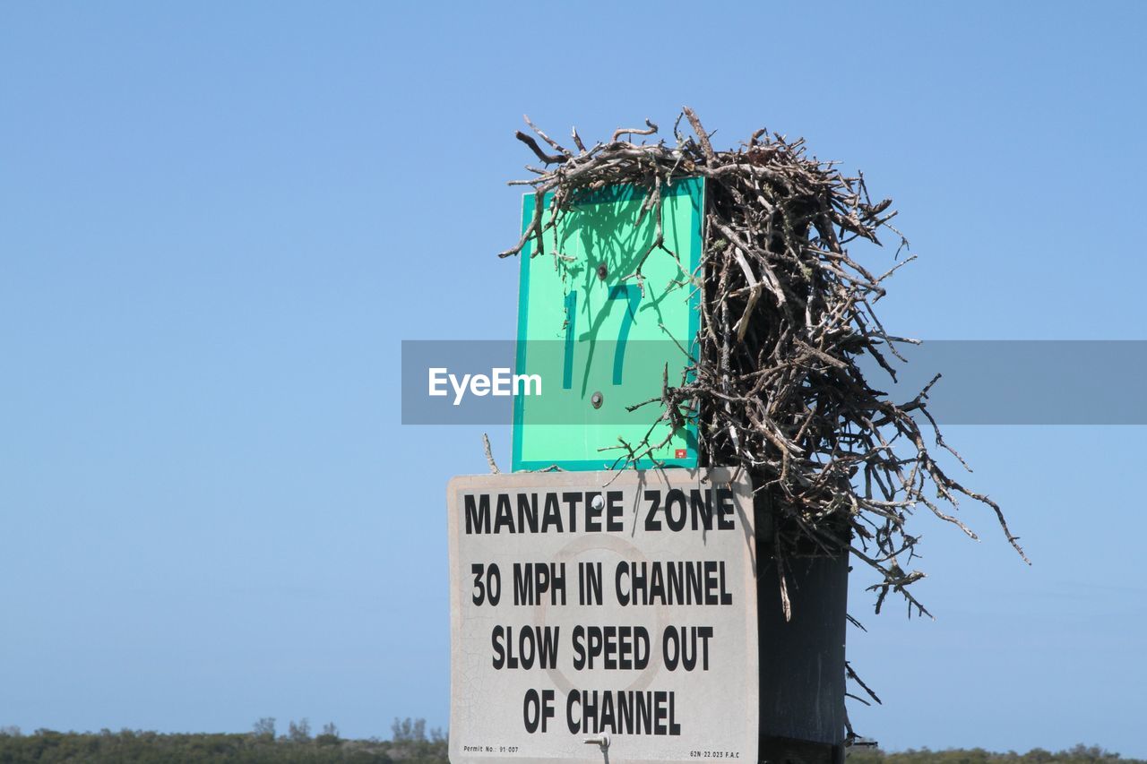 LOW ANGLE VIEW OF SIGN AGAINST CLEAR BLUE SKY