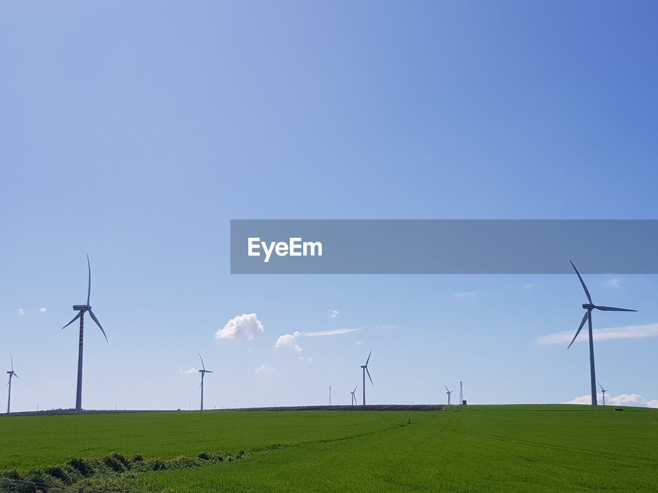 Windmill on field against blue sky