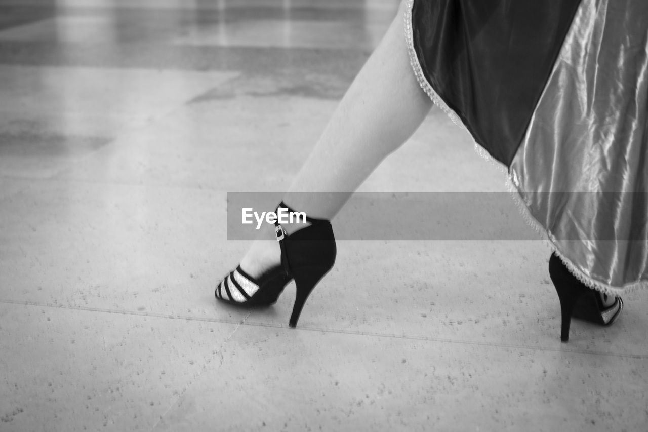 Low section of woman in high heels dancing on tiled floor