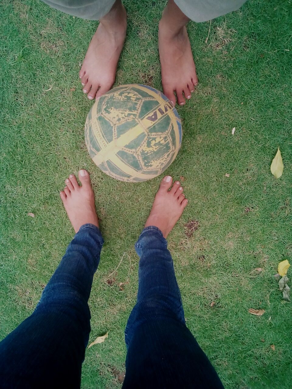 Low section of people standing by ball on field