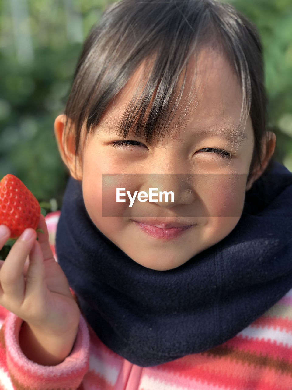 Close-up portrait of cute girl holding strawberry