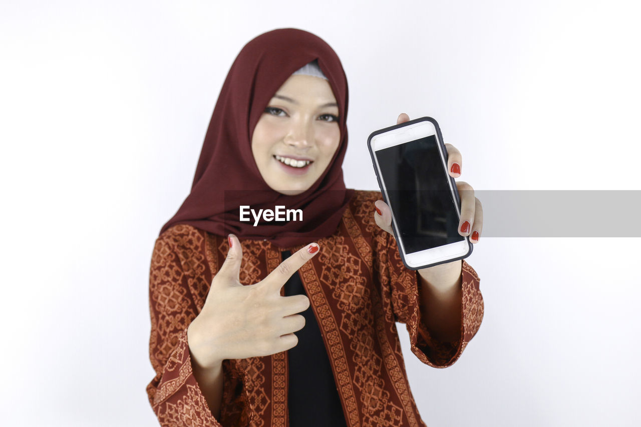 PORTRAIT OF A SMILING YOUNG WOMAN USING PHONE