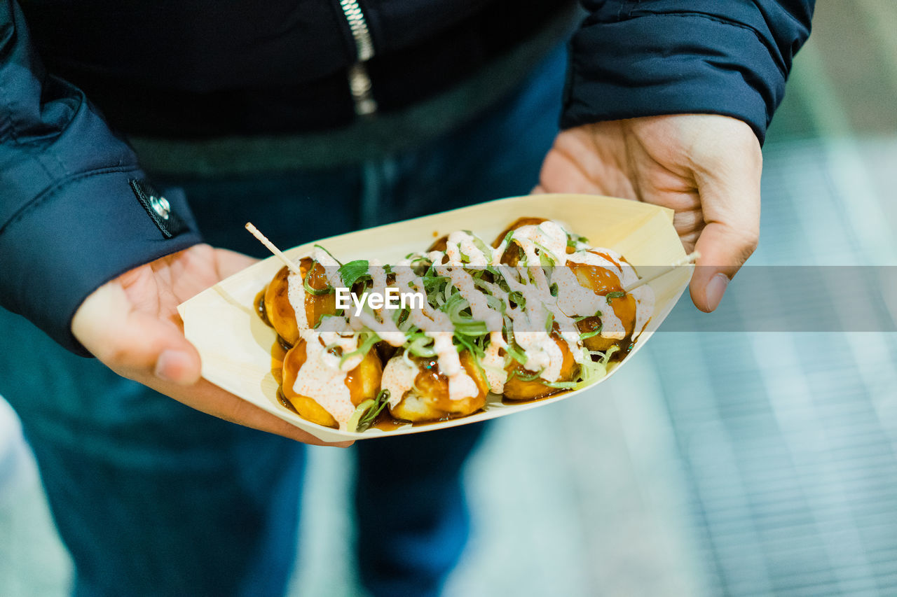 Midsection of man holding food takoyaki in japan