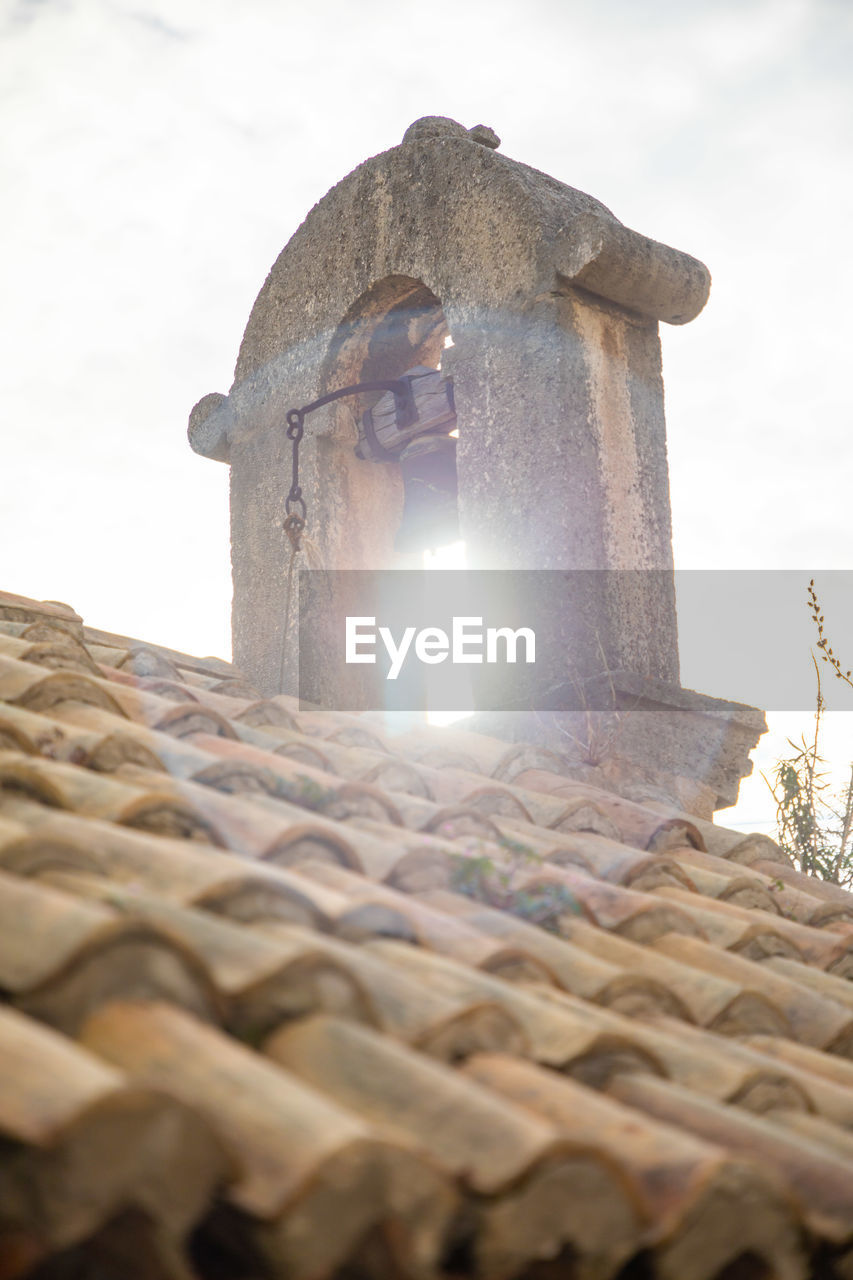 LOW ANGLE VIEW OF OLD BUILDING AGAINST SKY SEEN THROUGH CROSS