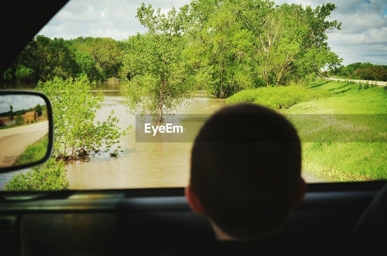 Rear view of boy in looking towards river while sitting in car