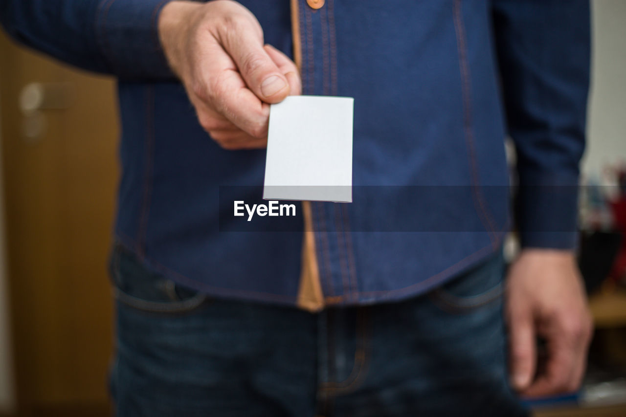 Midsection of man holding paper