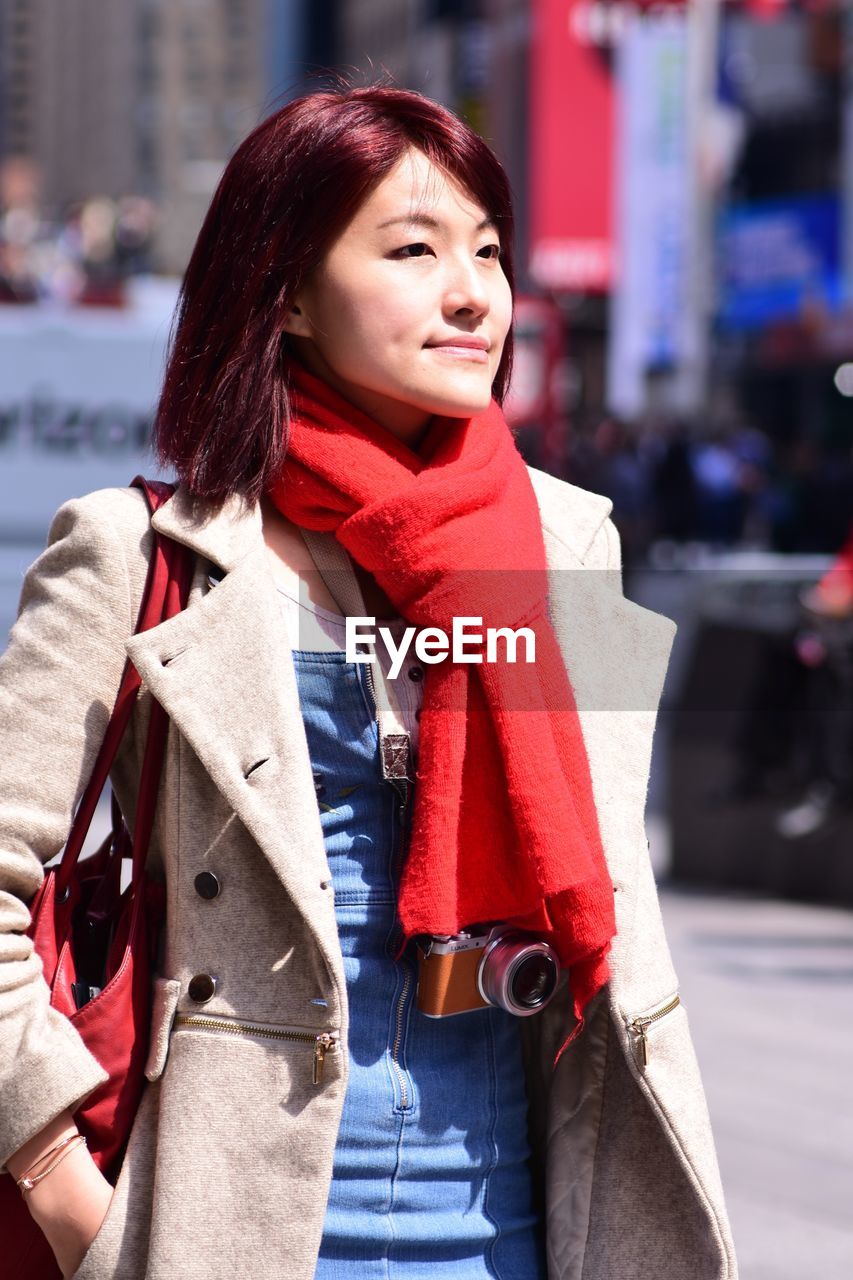 Young woman in warm clothes standing in city during winter