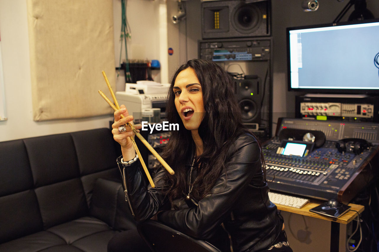 Young woman holding drumsticks in a recording studio