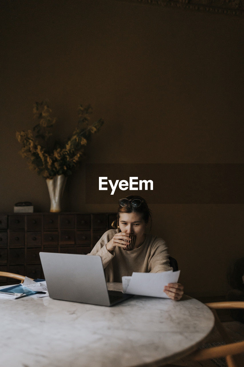 Non-binary person examining finance bills while sitting at home